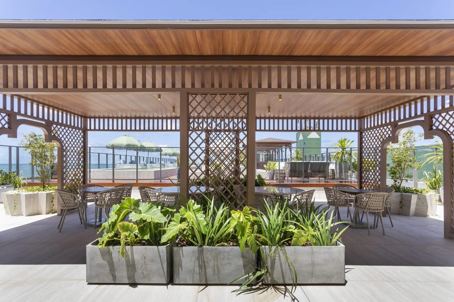 Terraço coberto da cobertura, com treliças de madeira, jardineiras e vista para o mar
